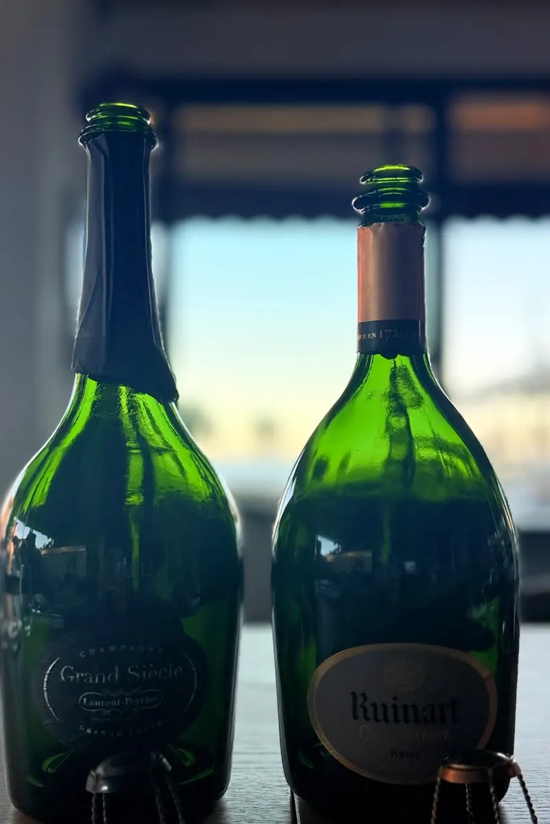 Bouteilles de champagne Laurent-Perrier Grand Siècle et Ruinart devant la baie vitrée